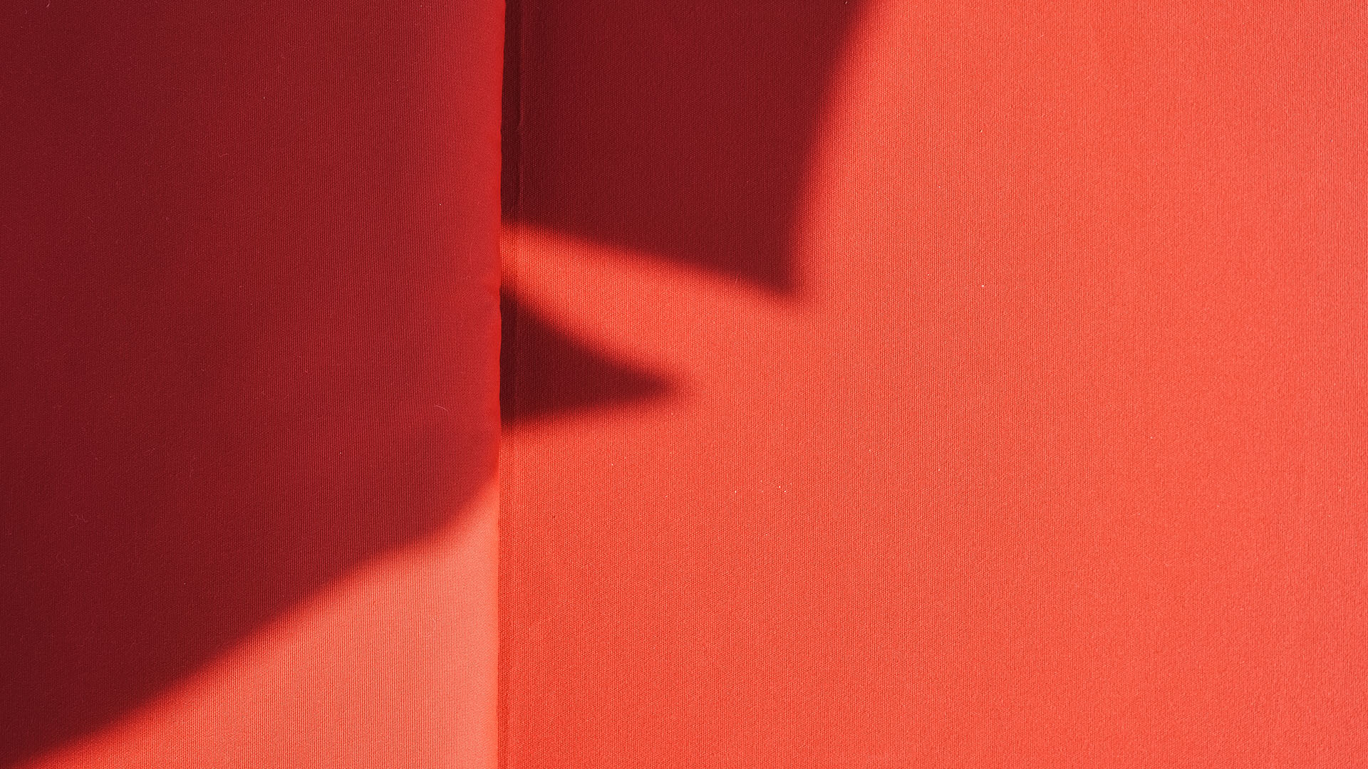 Primo piano del tessuto tecnico color terracotta di un lettino a bordo piscina, con gioco di luci e ombre geometriche, nell'area relax di Poggio al Casone.