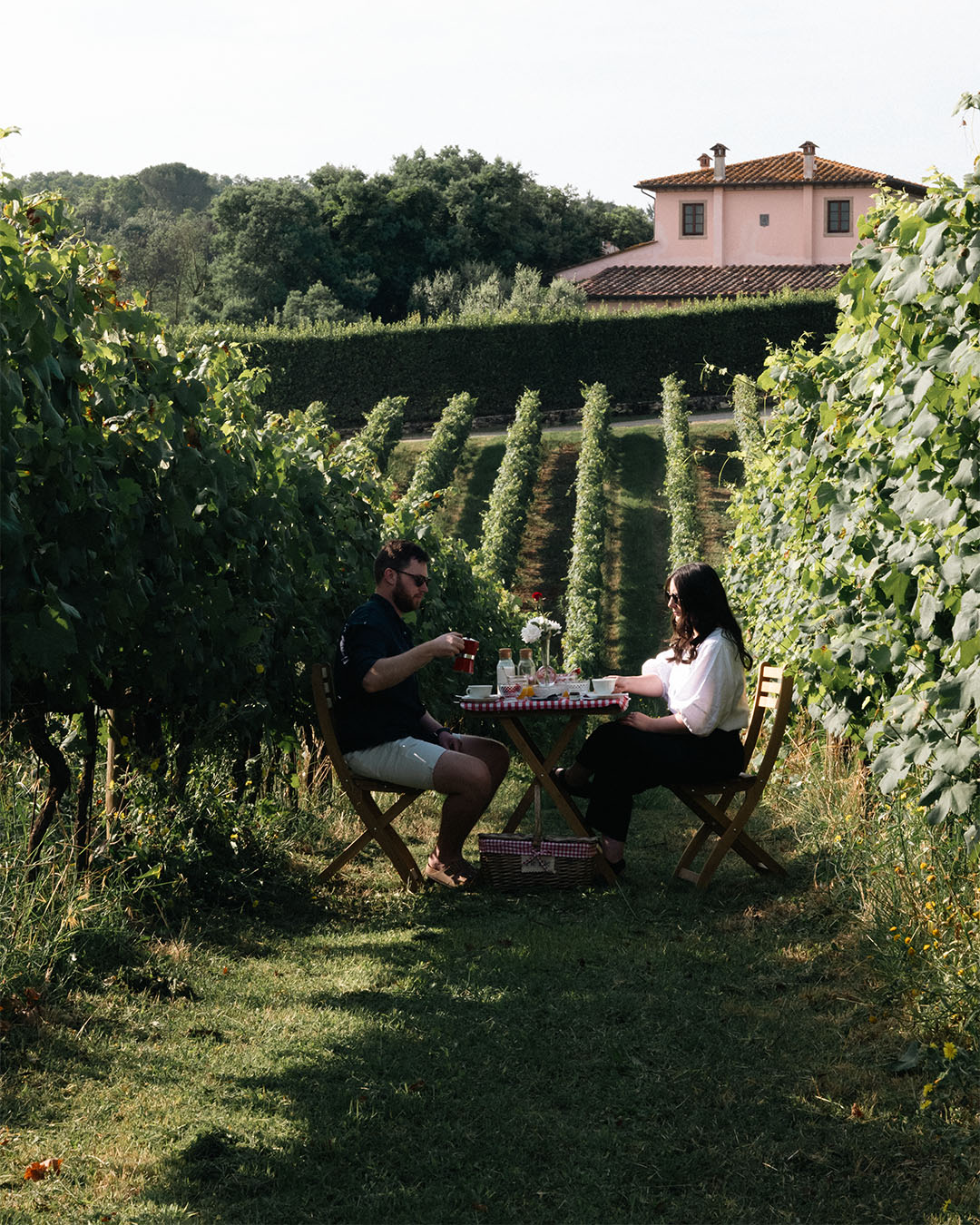 Coppia che si gode un picnic romantico e una degustazione di vini tra i filari dei vigneti della Tenuta Poggio al Casone in Toscana.