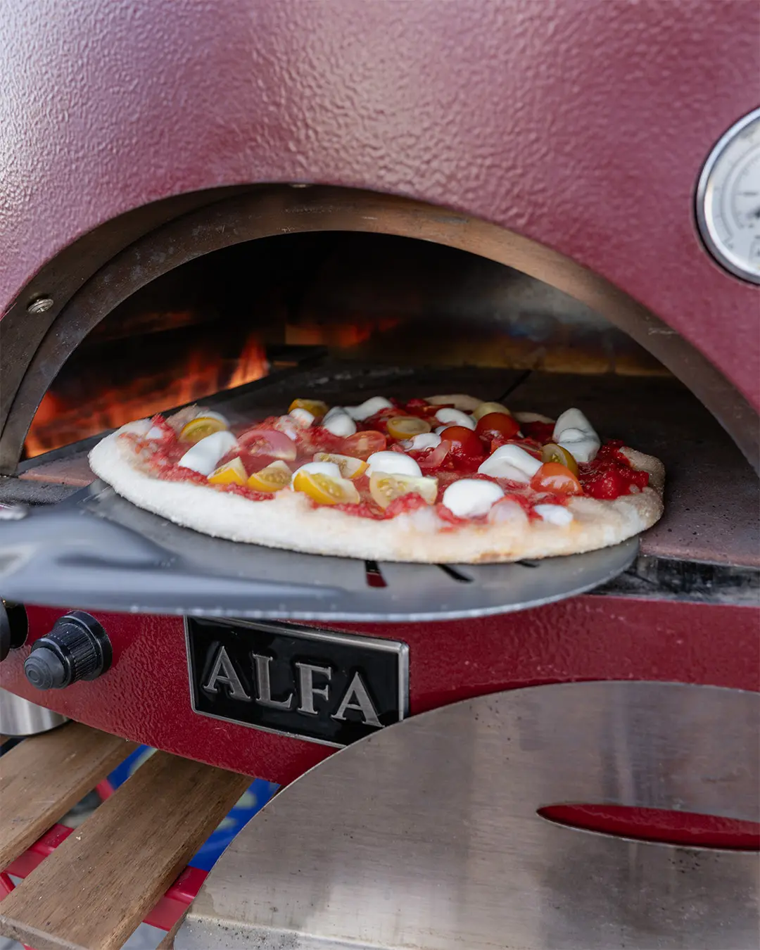 Pizza artigianale con ingredienti biologici in cottura nel forno a legna durante la Pizza Night in Toscana.